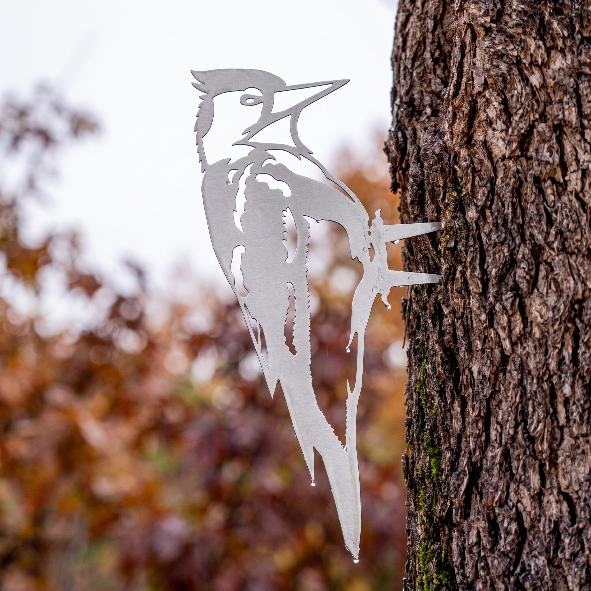 Woodpecker Stake metal yard art in raw steel finish, autumn setting