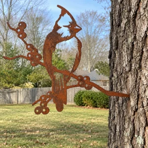 Rust-finish steel cardinal on a winter-berry branch, its spike set into a tree trunk in a backyard